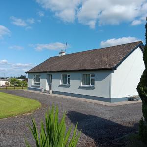 a white house with a gray roof and a driveway at Home from home in East Galway in Ballycrossaun