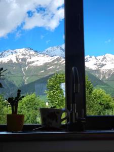 a view of snow covered mountains from a kitchen window at B&B Cottage in Mestia in Mestia