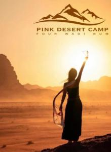 ワディ・ラムにあるPink Desert Campの砂漠の看板を持つ岩の上に立つ女