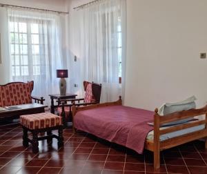a bedroom with a bed and a couch and chairs at Archontiko Taxiarches Kymi Evia in Kymi