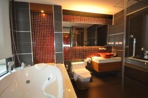 a bathroom with a tub and a toilet and a sink at Chalelarn Hotel Hua Hin in Hua Hin