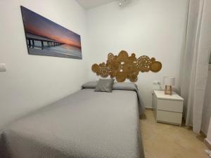 a bedroom with a bed and a picture on the wall at Vistas al mar a 10 metros de la Playa de Regla in Chipiona