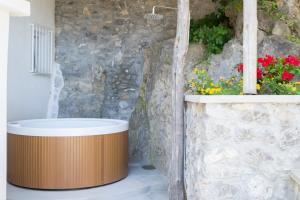 a bath tub sitting next to a stone wall with flowers at o' mar - Amalfi Coast Suite in Praiano