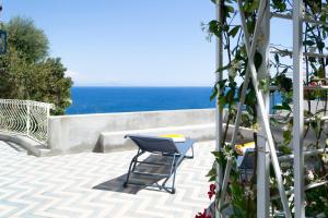 a chair on a patio with the ocean in the background at o' mar - Amalfi Coast Suite in Praiano