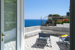 a patio with two chairs and a table and the ocean at o' mar - Amalfi Coast Suite in Praiano