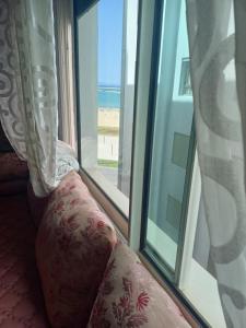 eine Couch vor einem Fenster mit Meerblick in der Unterkunft Apartment soultana in Tangier
