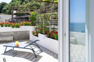 a bench sitting on a patio next to a flower garden at o' mar - Amalfi Coast Suite in Praiano