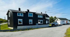 Czarny dom z ciężarówką zaparkowaną przed nim w obiekcie Explore Bugøynes w mieście Bugøynes