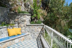 a bench with a yellow pillow on a stone wall at o' mar - Amalfi Coast Suite in Praiano