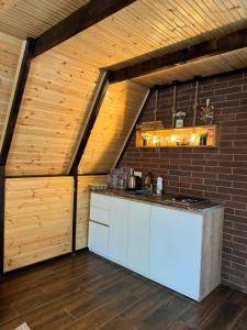 eine Küche im Dachgeschoss mit weißen Schränken und einer Ziegelwand in der Unterkunft cottage machakhela in Batumi