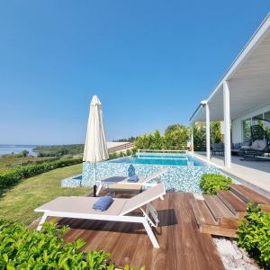 a pool with an umbrella and a chaise lounge next to a house at Villa Flamingo Lefkada in Ayía Varvára