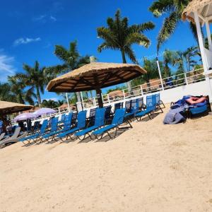 a group of chairs and umbrellas on a beach at VaeTropicalParadise Free Beach & Pool Access in Discovery Bay