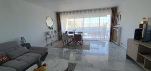 a living room with a couch and a table at Spacieux 2 pièces terrasse et piscine in Cannes