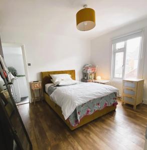 a bedroom with a bed with white sheets and a wooden floor at Pond Cottage in Purley
