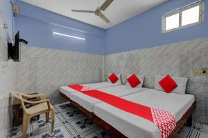 een slaapkamer met een bed met rode en witte kussens bij OYO Flagship Sai Ganesh Deluxe Lodge in Tirupati