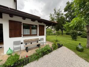 uma casa com um banco ao lado de um jardim em La Dolce Vita. Alloggio nel verde cuore del Friuli Venezia Giulia em Mariano del Friuli