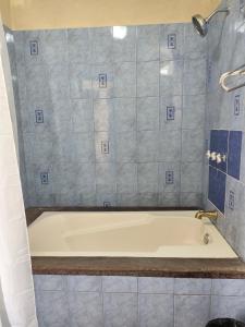 a bath tub in a bathroom with blue tiles at Hotel Restaurante La Villa de los Dioses in San Antonio Palopó