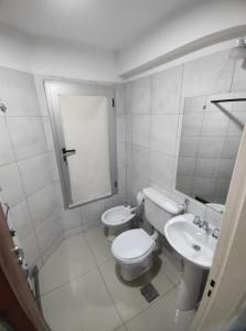 Baño blanco con aseo y lavamanos en Departamento completo en Rosario