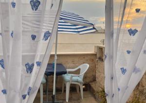 d'une table, de chaises et d'un parasol sur le balcon. dans l'établissement Casa Maya, Vista Mare e Relax, à Polignano a Mare