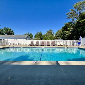 a swimming pool with chairs and a white fence at North Colony Motel and Cottages in Bartlett