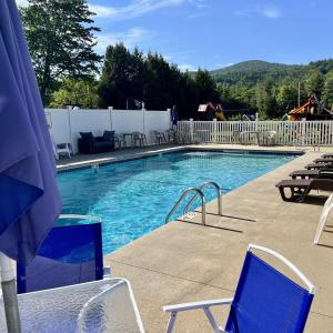 una piscina con sillas azules y una valla blanca en North Colony Motel and Cottages, en Bartlett