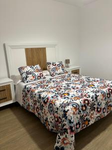 a bedroom with a bed with a floral comforter at Apartamento Isabel in Caravaca de la Cruz