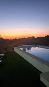 a large swimming pool with a sunset in the background at Monte do Rochinha in Monte da Cardosa