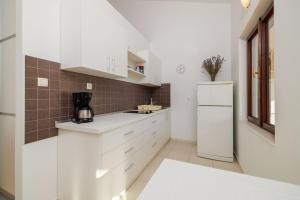 a kitchen with white cabinets and a refrigerator at Apartments Biserka in Palit