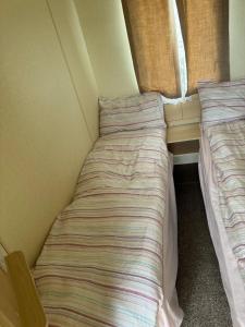 a small bedroom with two beds in it at HARTS Holiday Park Home in Leysdown-on-Sea +13 photos