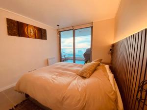 a bedroom with a bed with a large window at Departamento Concon con Terraza y vista al mar in Concón