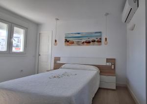 biała sypialnia z łóżkiem i obrazem na ścianie w obiekcie TU DENSCANSO EN VALDELAGRANA FRENTE AL MAR w mieście El Puerto de Santa María