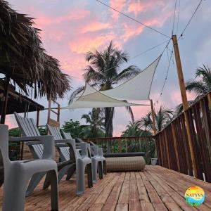 eine Terrasse mit Stühlen und einem Sonnenschirm auf einer Terrasse in der Unterkunft Natyva House in Guachaca