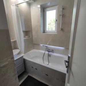 a bathroom with a tub and a sink and a window at Brook-Stone Beach Guesthouse in Sztutowo