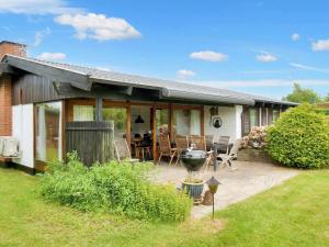 une maison avec une terrasse et un barbecue dans la cour dans l'établissement Holiday home Dronningmølle VII, à Dronningmølle