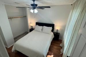 Un dormitorio con una cama blanca con ventilador de techo. en Little House in the Prairie, en Grand Prairie