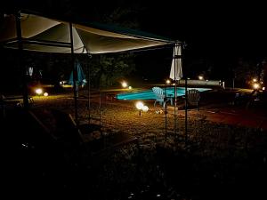 ein Pool in der Nacht mit zwei Stühlen und einem Sonnenschirm in der Unterkunft Domaine Plan des Devens in Roussillon