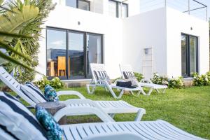 a group of white chairs sitting on a lawn at Cristy's Place in Cabouco