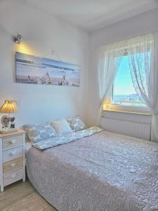 ein weißes Schlafzimmer mit einem Bett und einem Fenster in der Unterkunft Apartament Nice View -16piętro, parking podziemny, blisko morza in Danzig