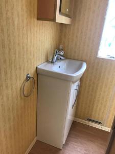 łazienka z białą umywalką i oknem w obiekcie Apartamenty i Domki WyDmy Międzywodzie w mieście Międzywodzie