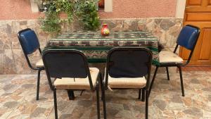 a table with three chairs and a vase on it at Los alamos in Humahuaca