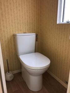 - białą toaletę w łazience z oknem w obiekcie Apartamenty i Domki WyDmy Międzywodzie w mieście Międzywodzie