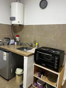 eine Küchentheke mit Mikrowelle und Spüle in der Unterkunft hospedaje LH E a 15 minutos del aeropuerto ezeiza in Ezeiza