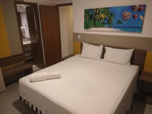 a bedroom with a white bed with a painting on the wall at Olímpia Thermas Resort in Olímpia