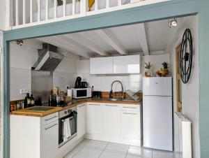 Una cocina con gabinetes blancos y un refrigerador blanco. en L'escale secrète - Emplacement central premium, en Nimes