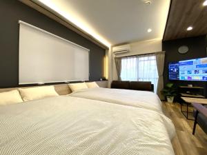 1 dormitorio con 2 camas y una pantalla grande en Frontier 1st Building - Vacation STAY 15474, en Kagoshima
