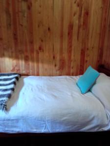 Una cama blanca con un libro azul encima. en Cabaña Gloria, en Coñaripe