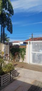 ein weißer Zaun mit einer Palme vor einem Gebäude in der Unterkunft Casa Térrea-Bertioga-Uso exclusivo para de 1 a 12 pessoas in Bertioga + 111 Fotos