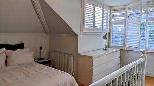 een slaapkamer met een bed, een dressoir en ramen bij Sun-Kissed Sanctuary by Battersea Park in Londen