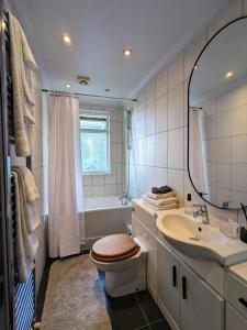een badkamer met een toilet, een wastafel en een bad bij Sun-Kissed Sanctuary by Battersea Park in Londen
