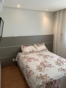 ein Schlafzimmer mit einem Bett mit rosa Blumen darauf in der Unterkunft Condomínio pé na areia com lazer completo - PCD in Barra Velha